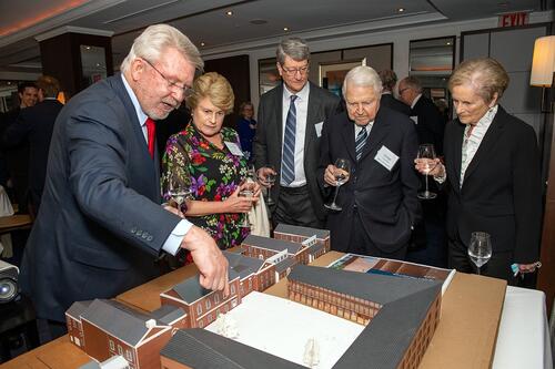A group of people leaned over, looking at an architectural model.